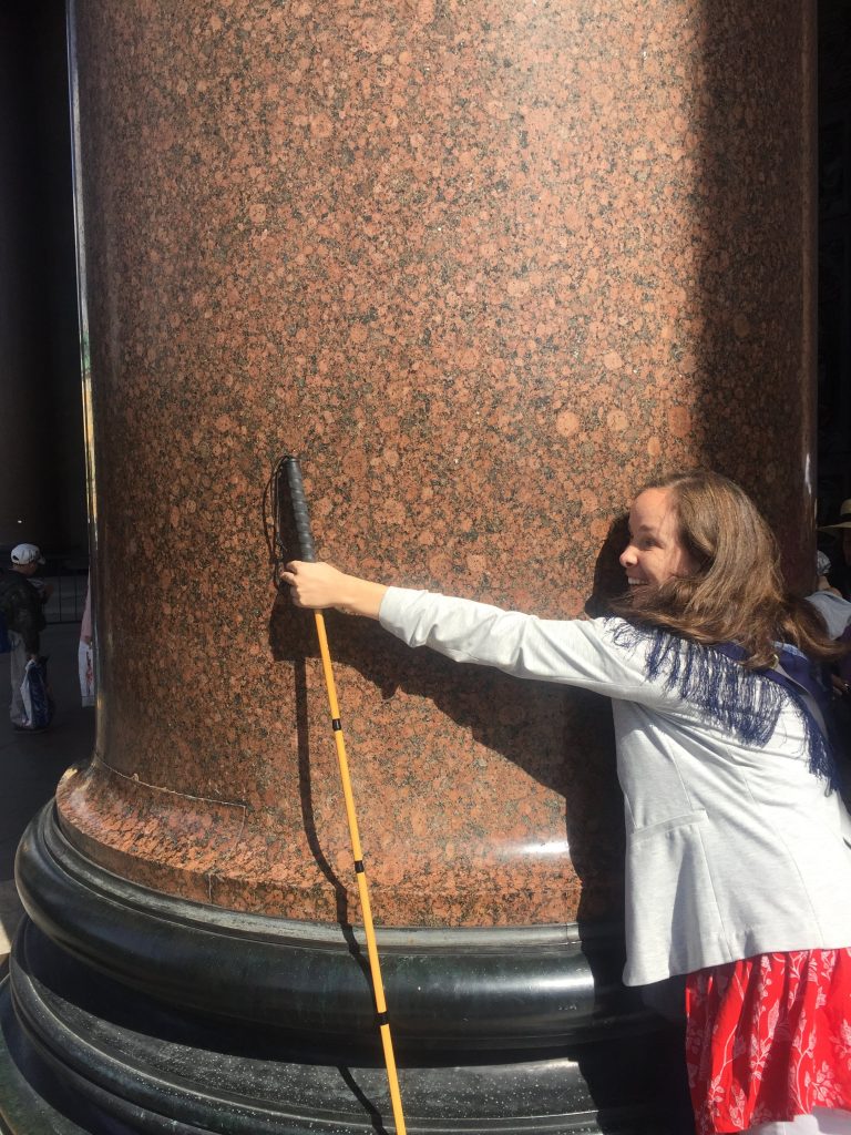 Inside Saint Isaac's Cathedral Laurel attempts to wrap her arms around a giant granite pillar. Laurel's arms are far to short to reach around the pillar.