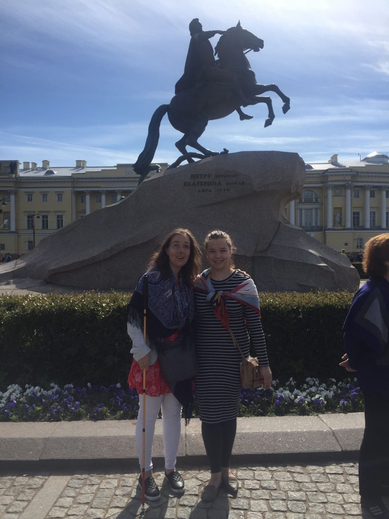 Laurel and Amy in front of the famous bronze horseman statue in St. Petersburg. A military dressed rider sits atop a horse that is rearing on its hind legs.